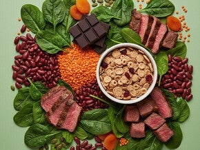 Uma variedade vibrante de alimentos ricos em ferro, como espinafre, lentilhas, carne e chocolate, dispostos artisticamente