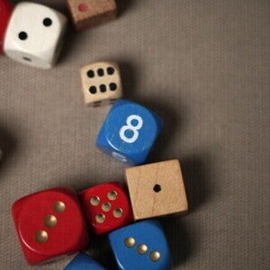 Dados coloridos de madeira e plástico, alguns vermelhos e azuis, sobre uma superfície marrom.