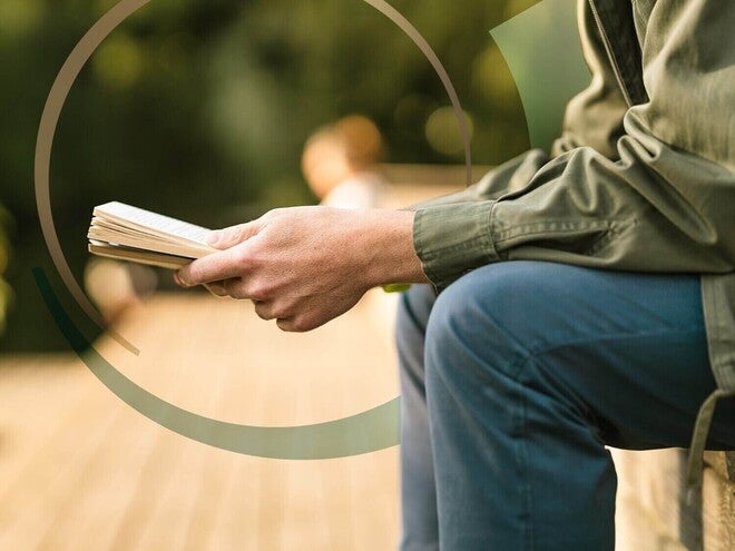 Pessoa adulta sentada ao ar livre lendo um livro e evitando telas