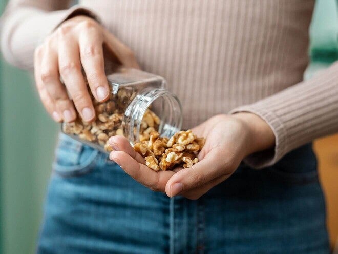 Mãos de uma mulher segurando um punhado de castanhas.