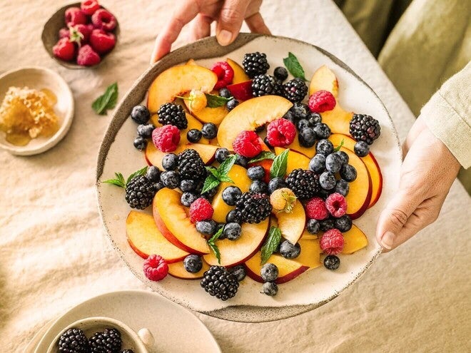 Prato com frutas variadas ricas em fibras: pêssegos, amoras, mirtilos e framboesas.