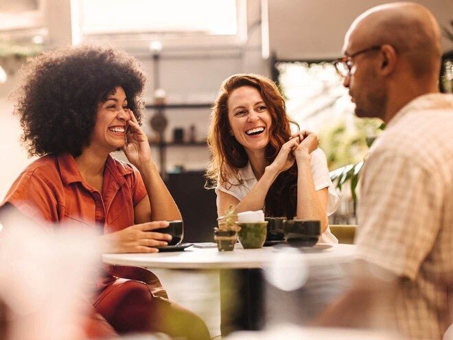Cena acolhedora de amigos conversando e rindo juntos. Conexões sociais para saúde emocional.
