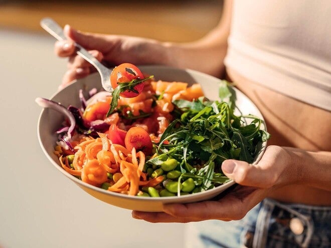 Prato com vegetais coloridos, como tomates, cenoura ralada, cebola, leguminosas e folhas verdes.