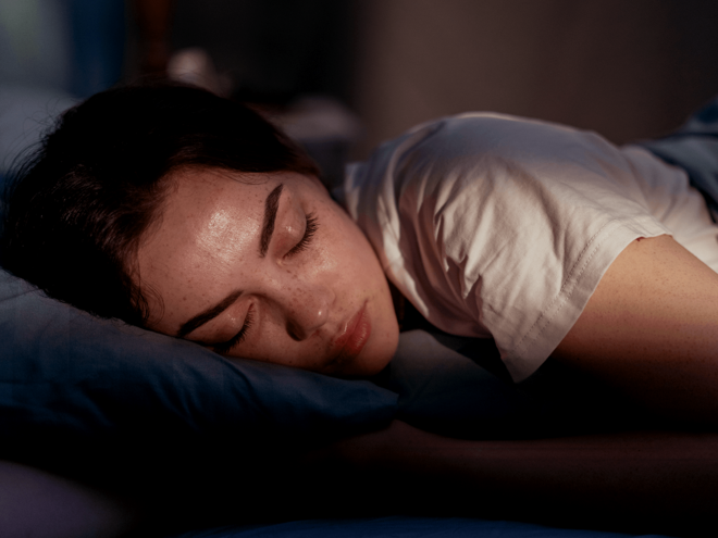 Mulher adulta deitada na cama pronta para dormir.