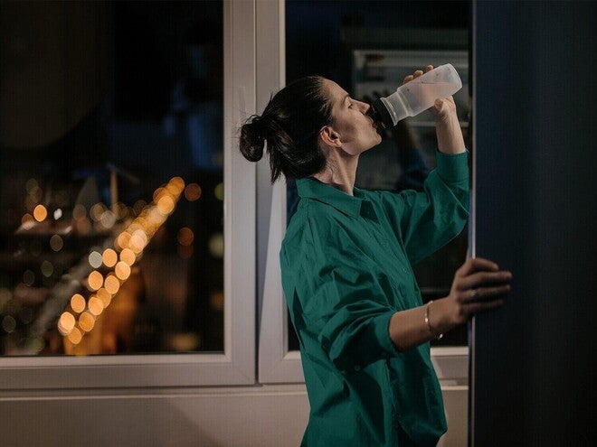 Mulher bebendo água à noite.