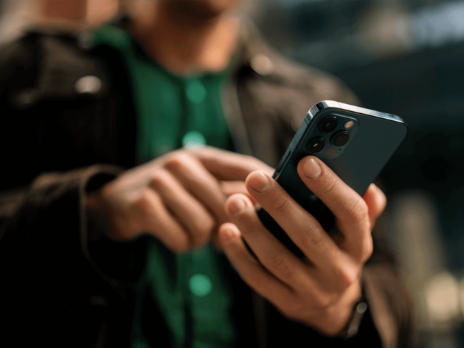 Mãos de um homem segurando um smartphone.