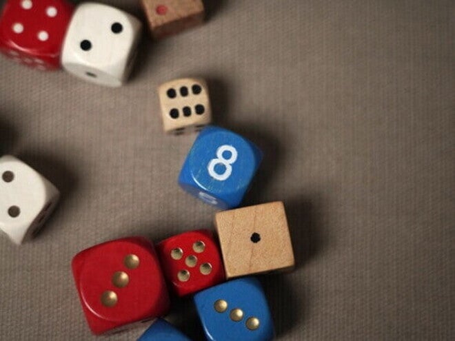 Dados coloridos de madeira e plástico, alguns vermelhos e azuis, sobre uma superfície marrom.