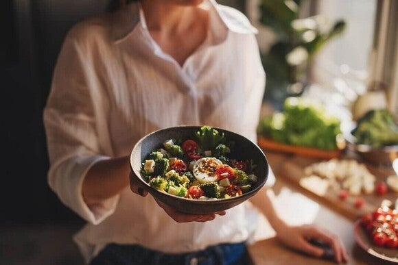Mulher com saladeira de couve, brócolis, ovo e tofu para prevenir a sarcopenia.