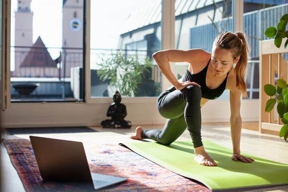 Mulher em um tapete fazendo yoga dinâmico.