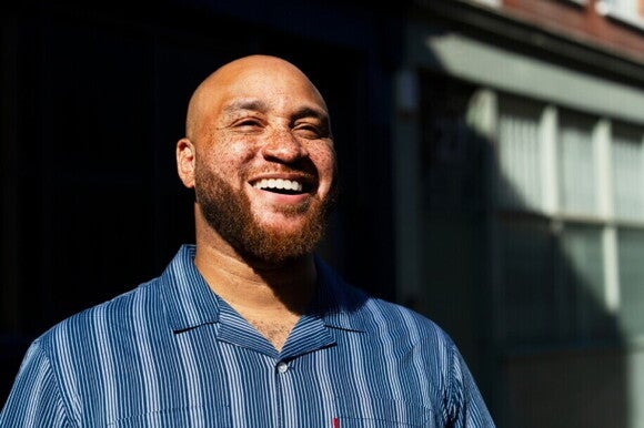 Homem careca sorrindo ao ar livre.